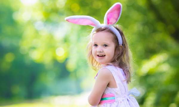 A little girl with bunny ears on her head 