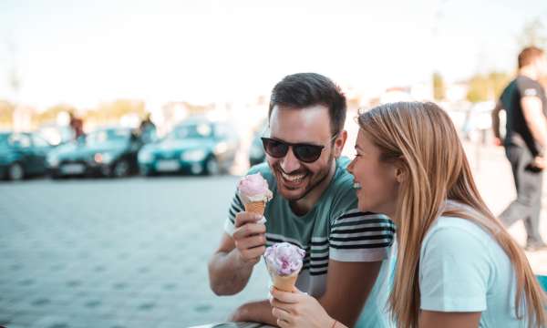 A couple enjoying ice creams in town and laughing