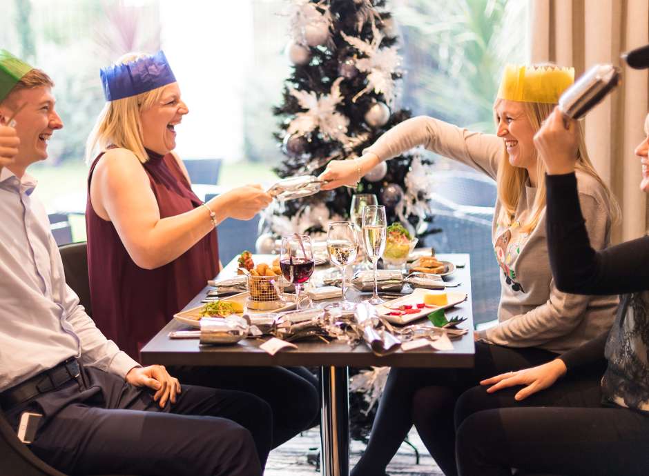 People pulling Christmas crackers xmas party lunch