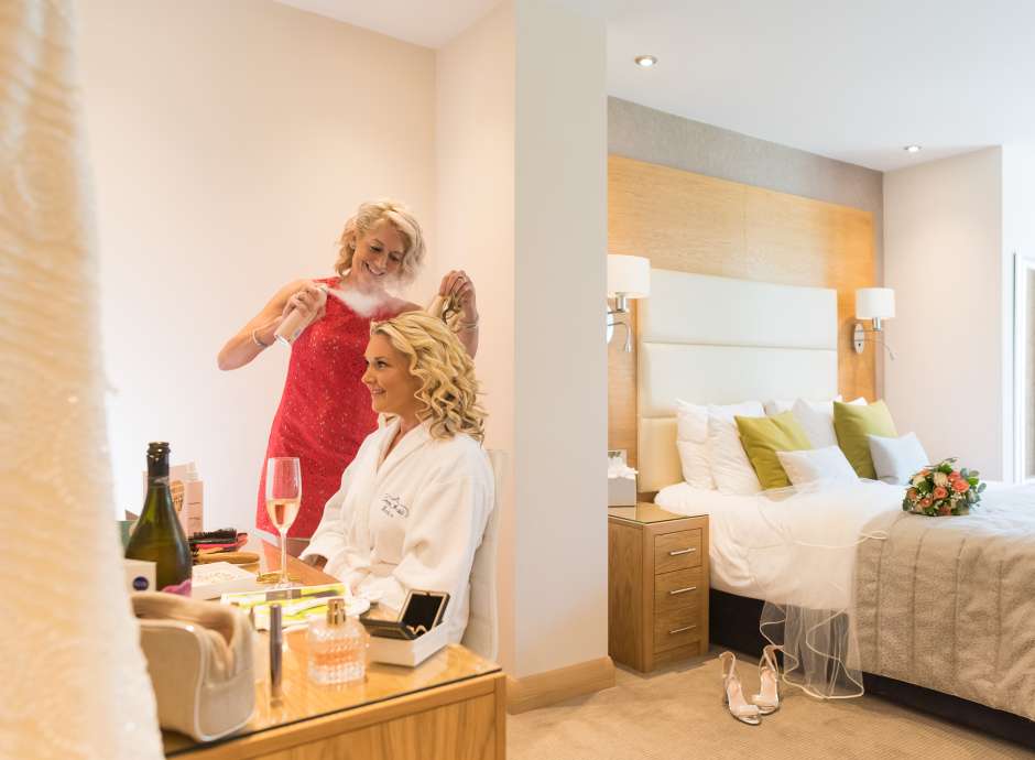 Bride drinking a glass of champagne whilst getting ready for her wedding